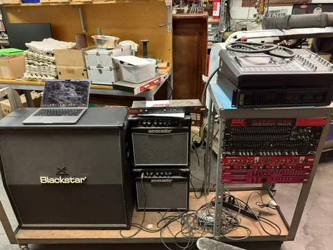Amplifiers and rack-mounted audio processors on a workshop bench